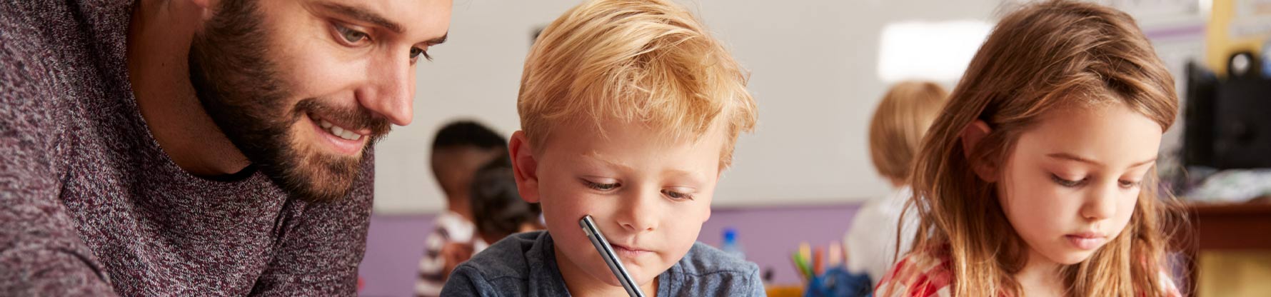 Ein Lehrer hilft einem Jungen und einem Mädchen bei den Aufgaben