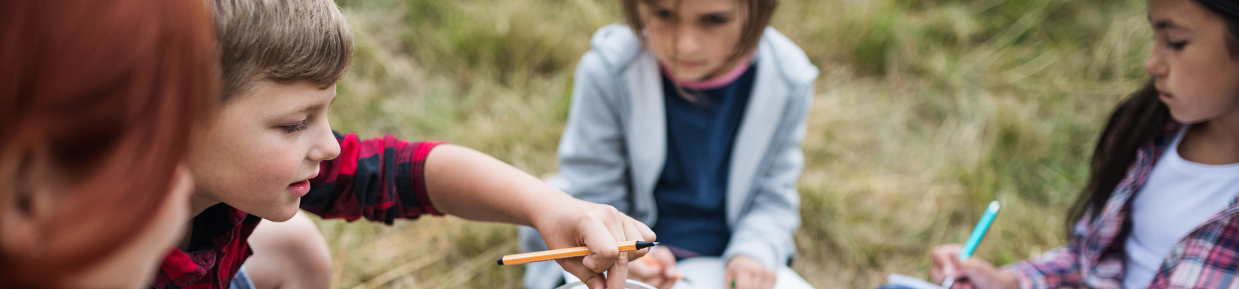 Eine Gruppe Kinder beim Experimentieren auf einer Wiese