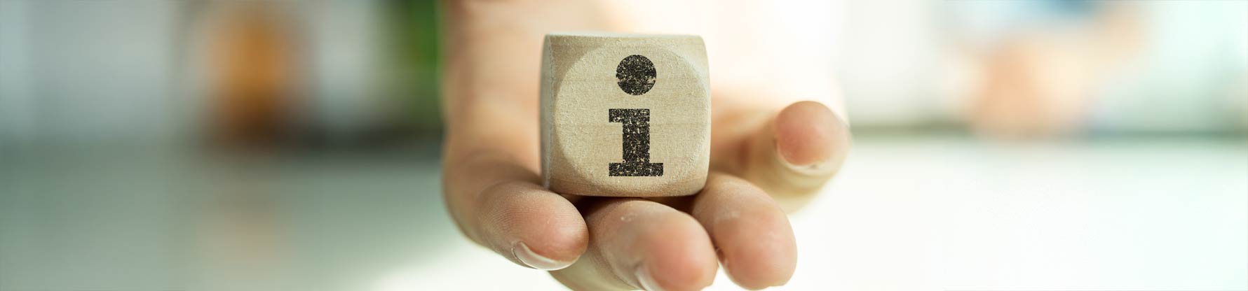 Eine Hand hält einen Holzwürfel mit dem Buchstaben i