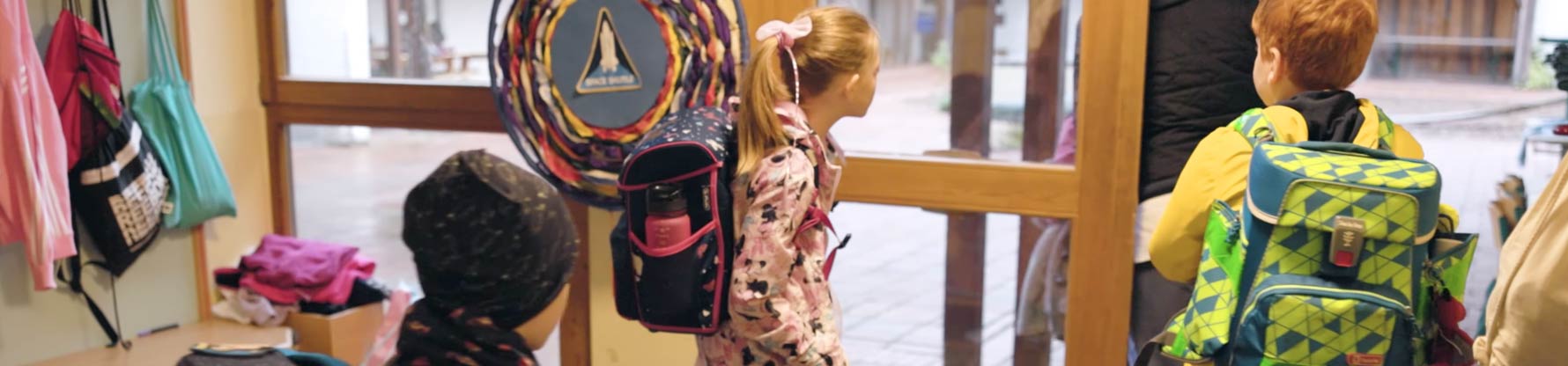 Kinder mit Jacken und Schulranzen verlassen die Garderobe in der Schule