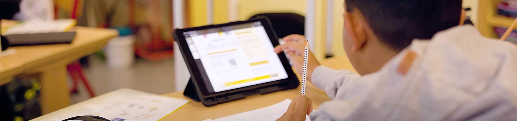 Eine Junge arbeitet in der Klasse an einem Tablet